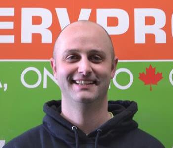 Bald male employee smiling in front of our SERVPRO truck